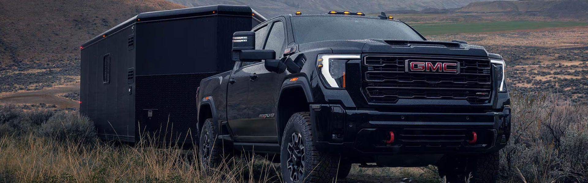 Black GMC heavy-duty pickup truck towing a large enclosed trailer