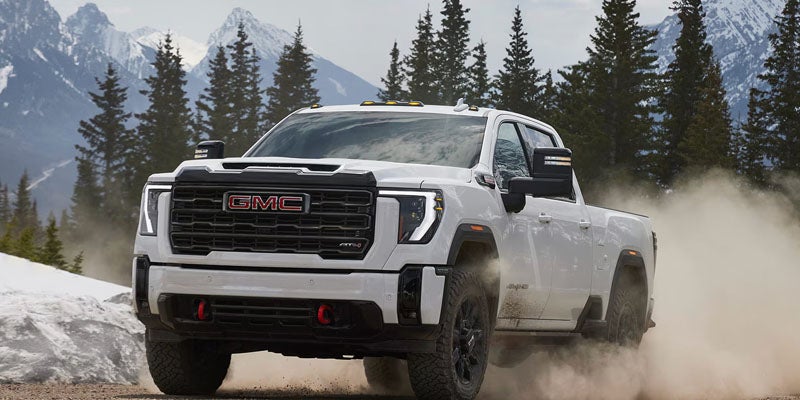 White GMC heavy-duty pickup truck driving on a dirt road